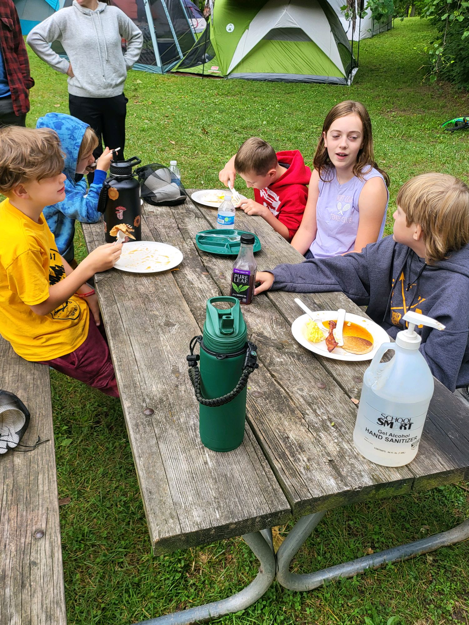 Scouts sharing a meal around the picnic table at the campsite