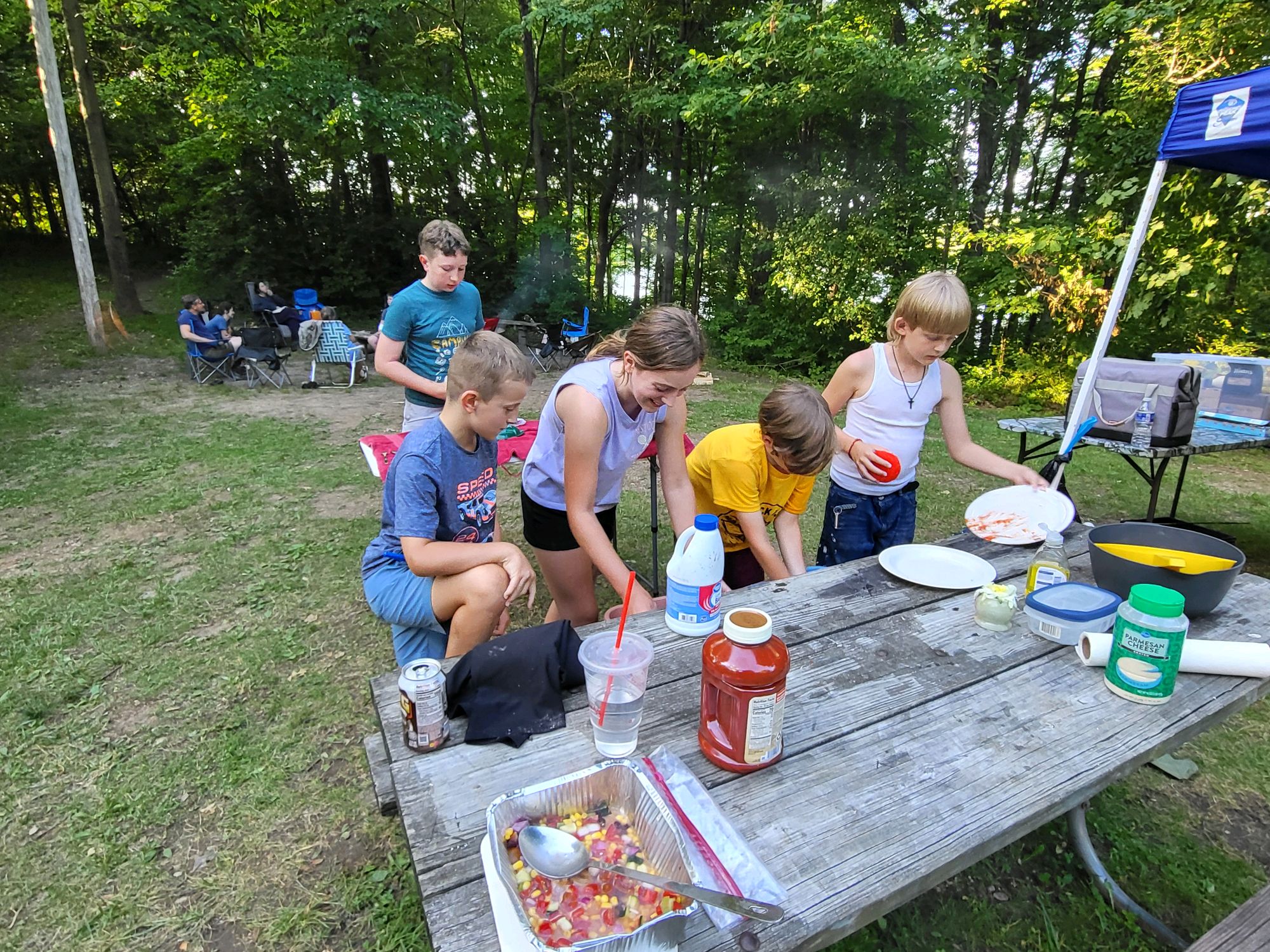 Scouts cleaning up dinner dishes at the campsite picnic table