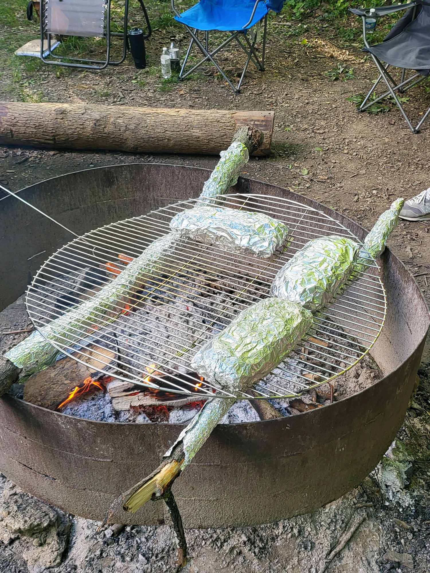 Foil-wrapped campfire meals cooking over hot coals