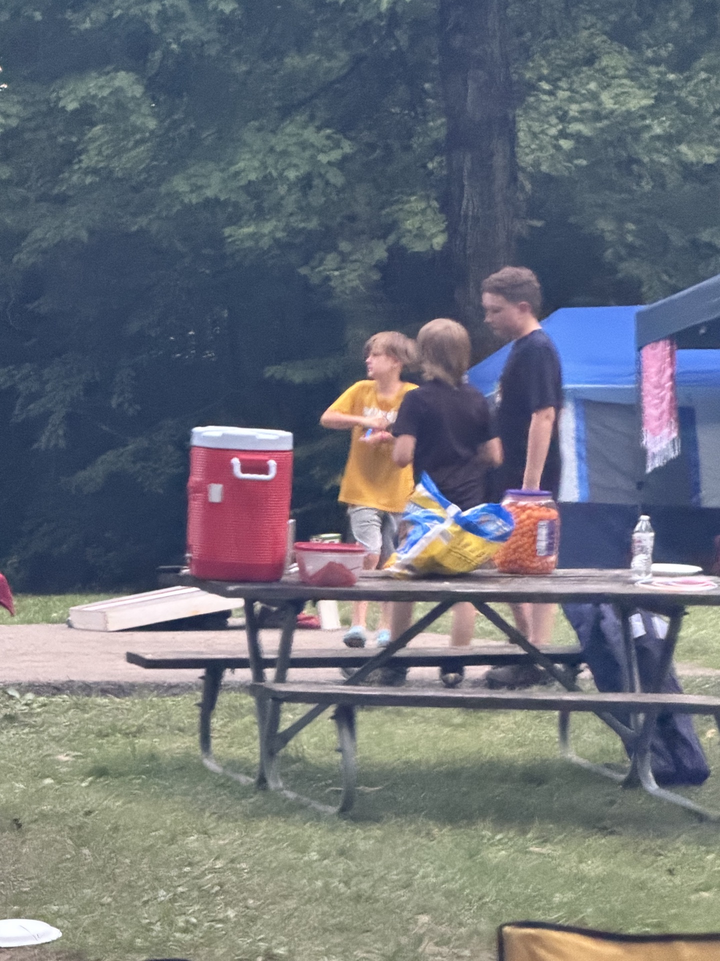 Scouts gathered at a campsite picnic table at dusk