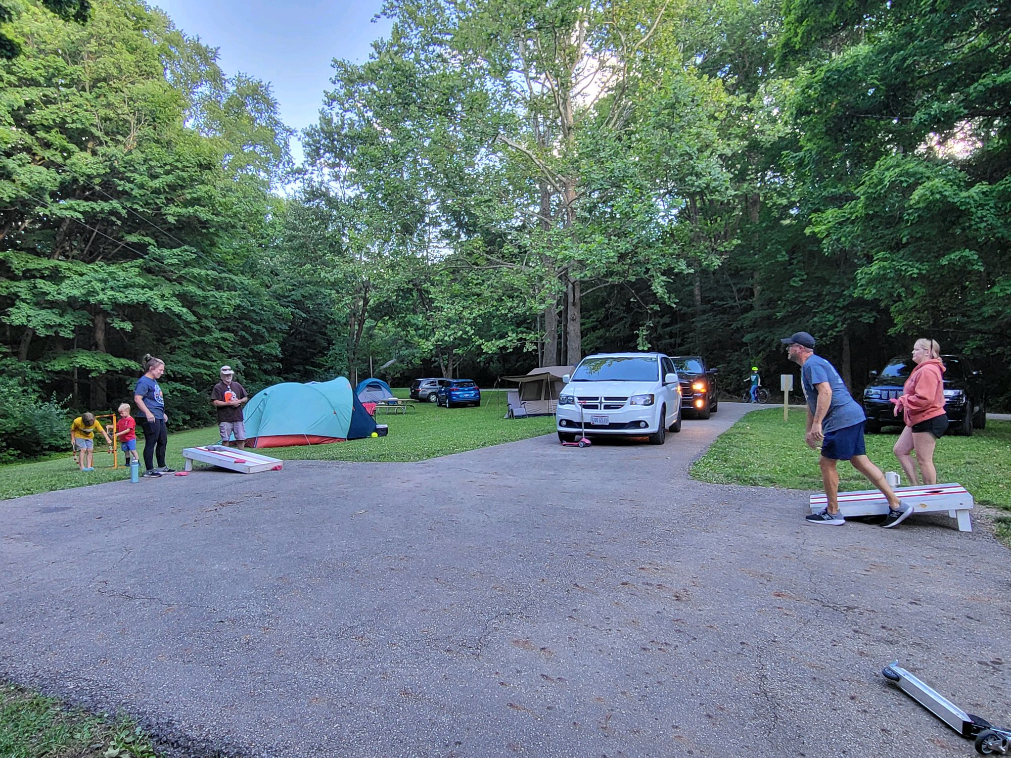 Families playing cornhole and ladder toss at the campsite in the evening