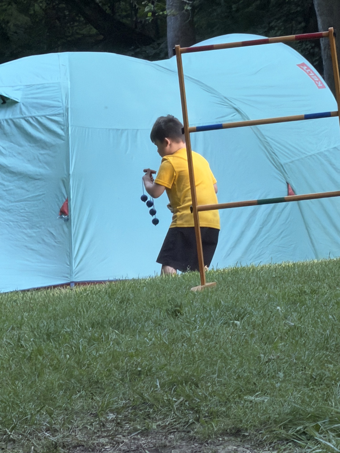 Scout playing ladder toss beside a tent at camp