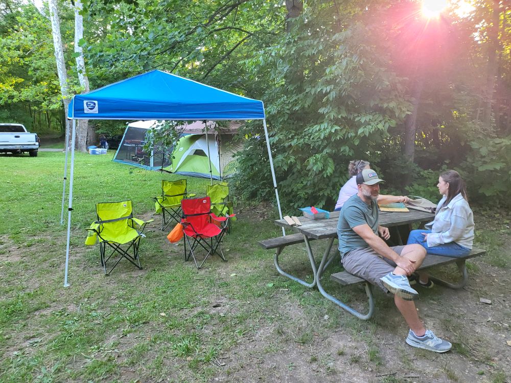 Canopy, chairs, and picnic table in the evening light at camp